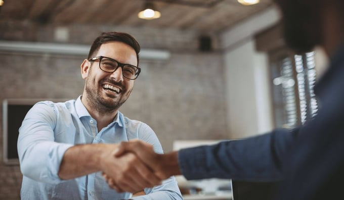 Man in glasses shakes hand of colleague in business deal